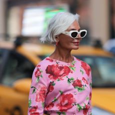 Bond repair hair products - Grece Ghanem is seen wearing sunglasses with white frame from Bottega Veneta, red hoop earrings with pearls, a pink cropped cardigan with red/green flower pattern - gettyimages 1681233409