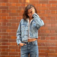 a woman wearing a denim jacket and low-rise jeans with a white hoodie