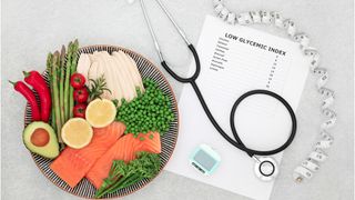 How do continuous glucose monitors work: An image showing a plate of salmon, avocados, peas and asparagus next to a stethoscope and a sheet of paper titled low glycemic index