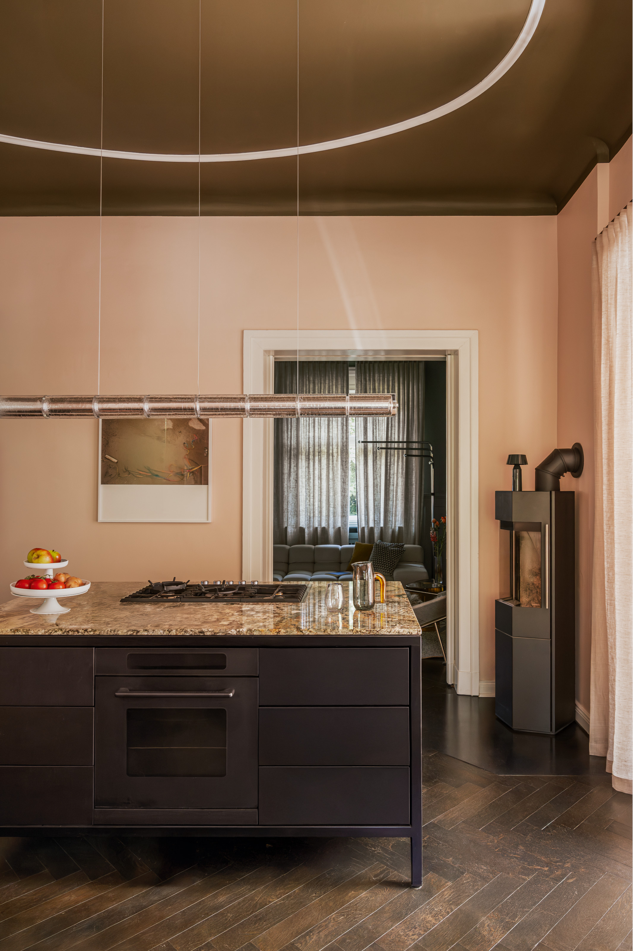 Kitchen with plaster pink walls, brown ceiling, brown island with brown terrazzo countertop and dark wood herringbone floor