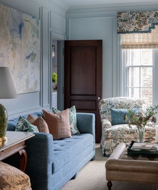 living room with light blue walls, blue sofa and muted orange pillows