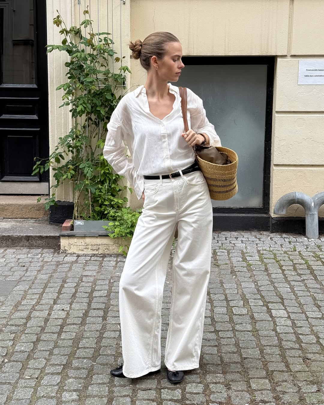 Clara in white button-down top and white wide-leg jeans