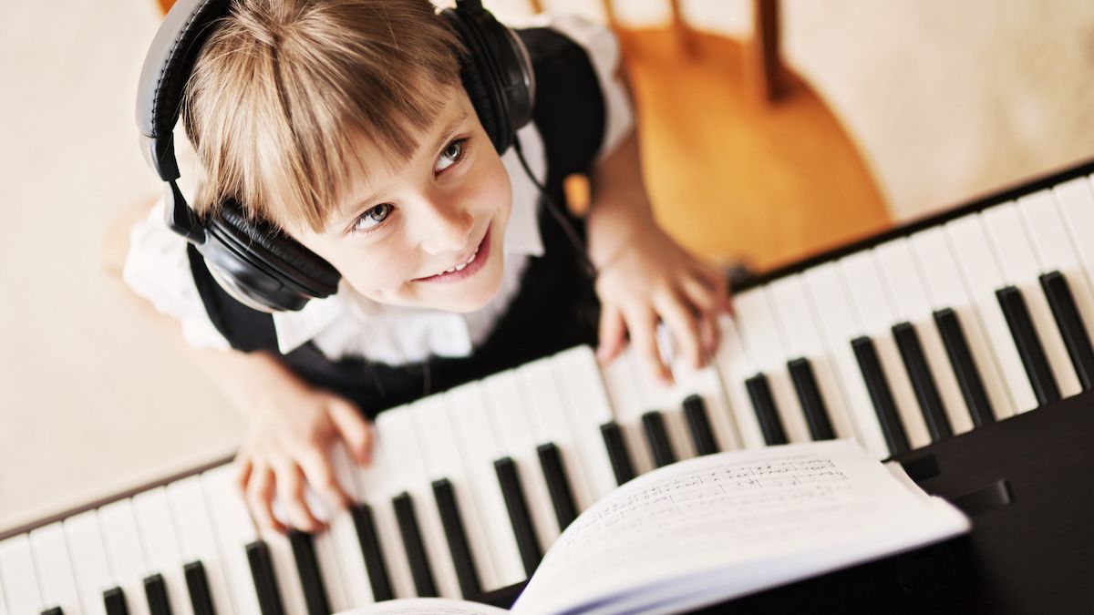 Young girl smiling at the camera while sat behind a keyboard