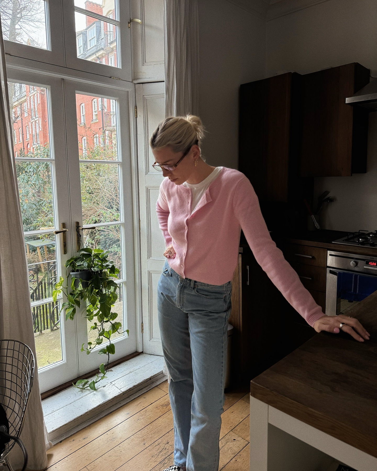 Influencer @lindseyholland_ wears a pink cardigan with blue jeans over a white t-shirt.