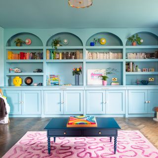 A built-in bookcase colour drenched in a sky blue shade with arched openings and bottom cabinet doors