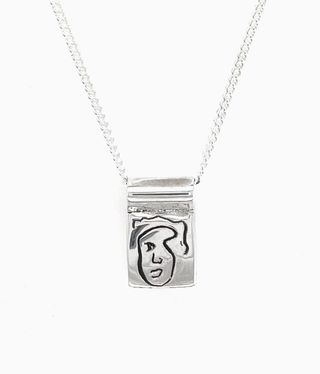 Silver chain with a face on the pendant.