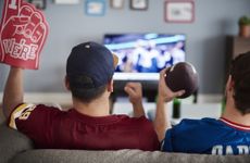 Two people are streaming football on TV sitting on a couch