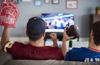 Two people are streaming football on TV sitting on a couch 
