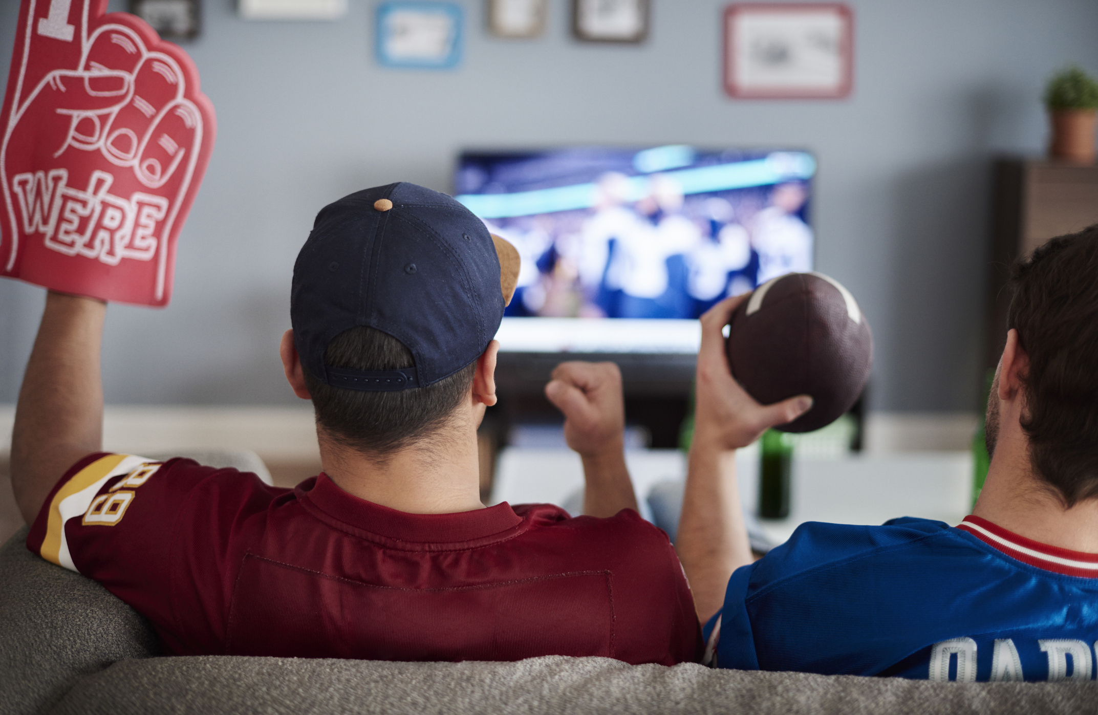 Two people are streaming football on TV sitting on a couch 