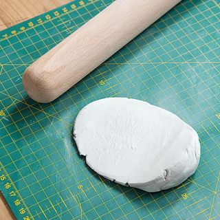 clay on cutting craft board with wooden rolling pin