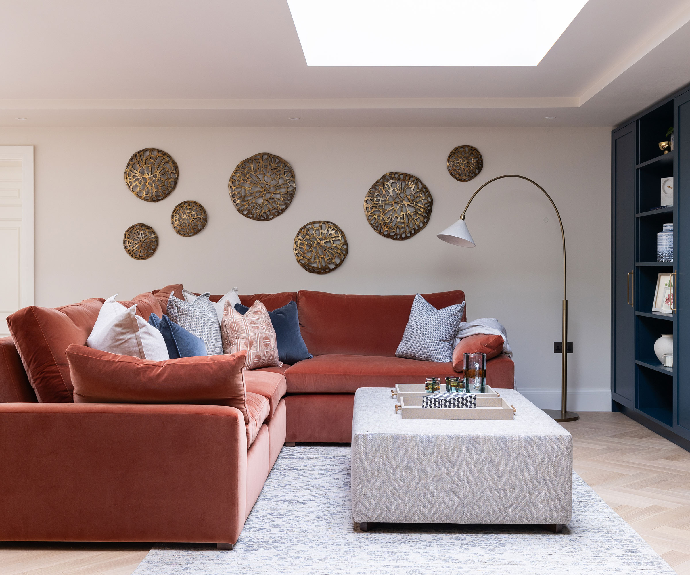 modern living room with red velvet L-shaped sofa and blue fitted shelving