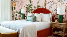 Bedroom with red bedstead and forest wallpaper