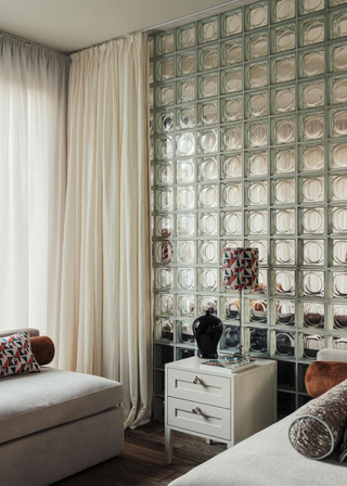 A bedroom with a glass block feature behind a curtain