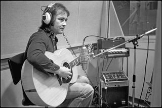 Mick Jones playing acoustic guitar in the studio, 1976