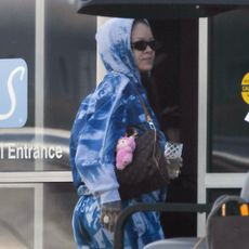 Rihanna arrives at the airport in a tie-dye sweatsuit with three designer bags by Dior and Louis Vuitton