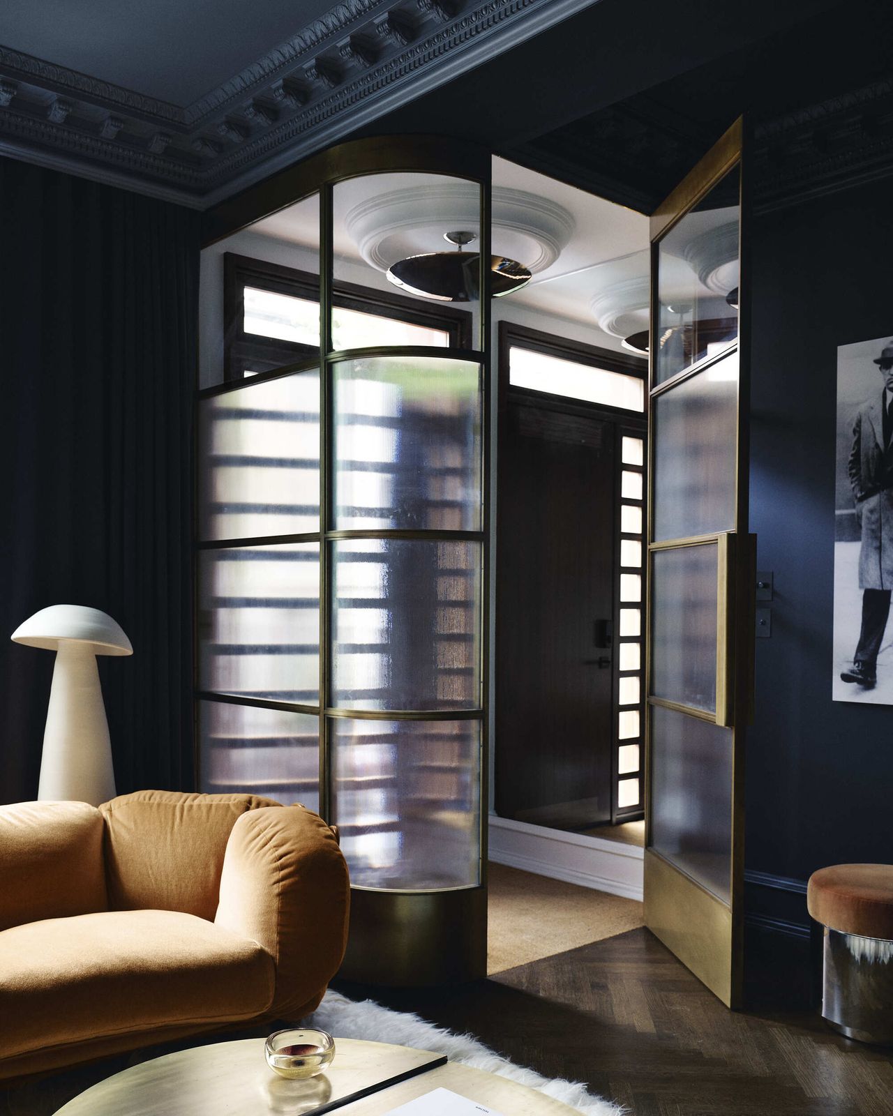 Image of a dark navy blue room with an entryway that is enclosed in a brass and glass case.