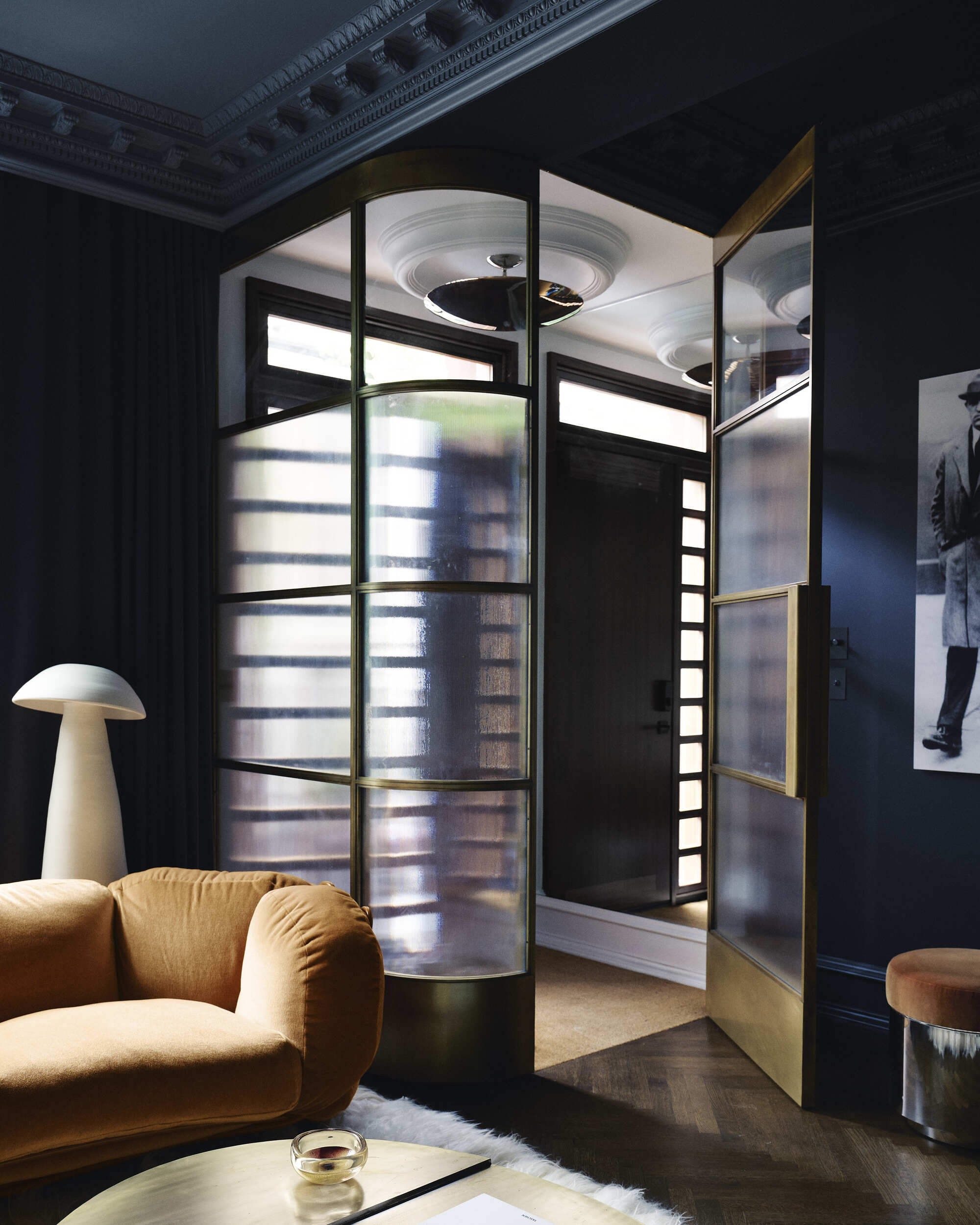 Image of a dark navy blue room with an entryway that is enclosed in a brass and glass case.