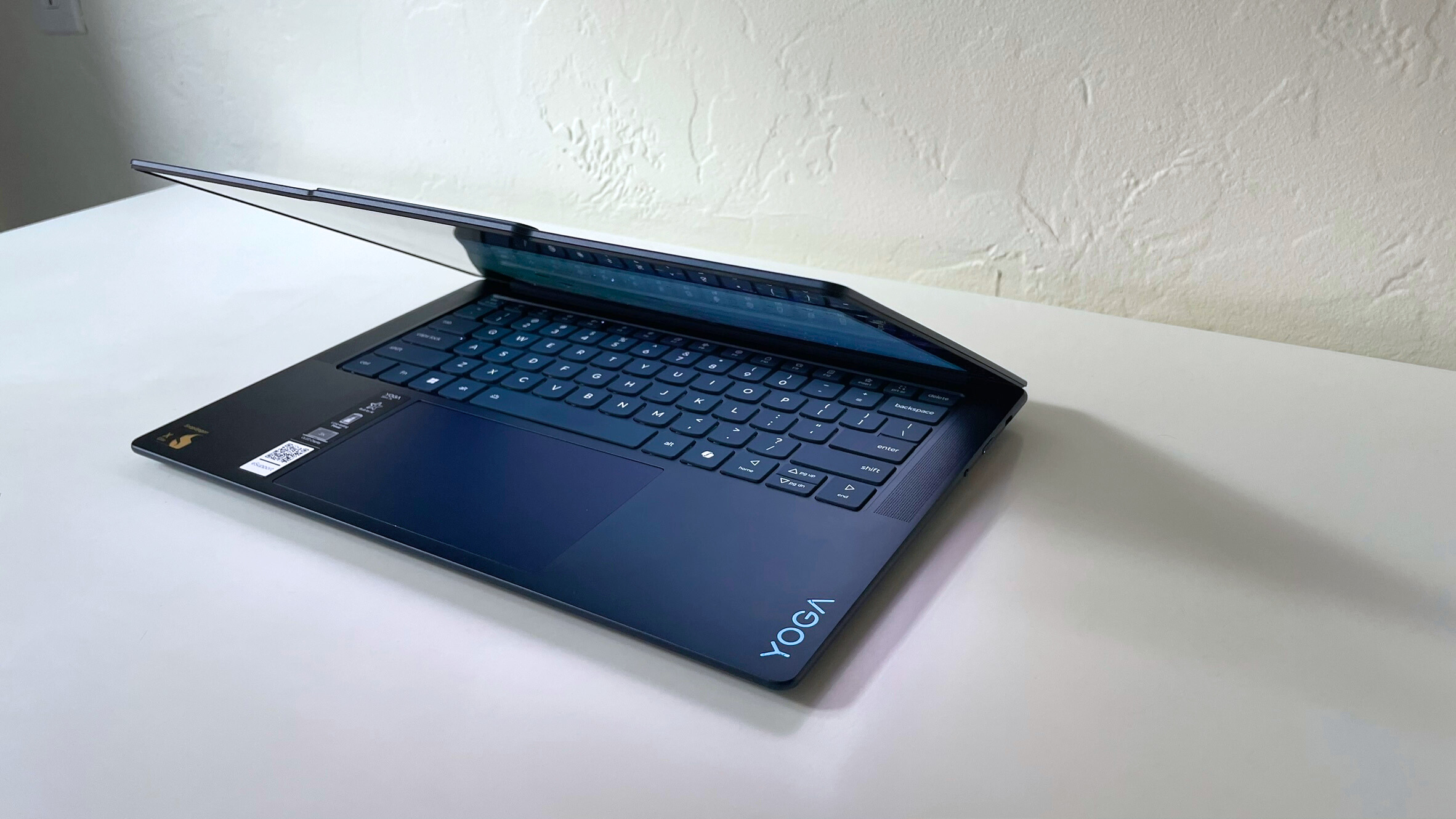 The Lenovo Yoga Slim 7x with the lid cracked open and keyboard deck illuminated