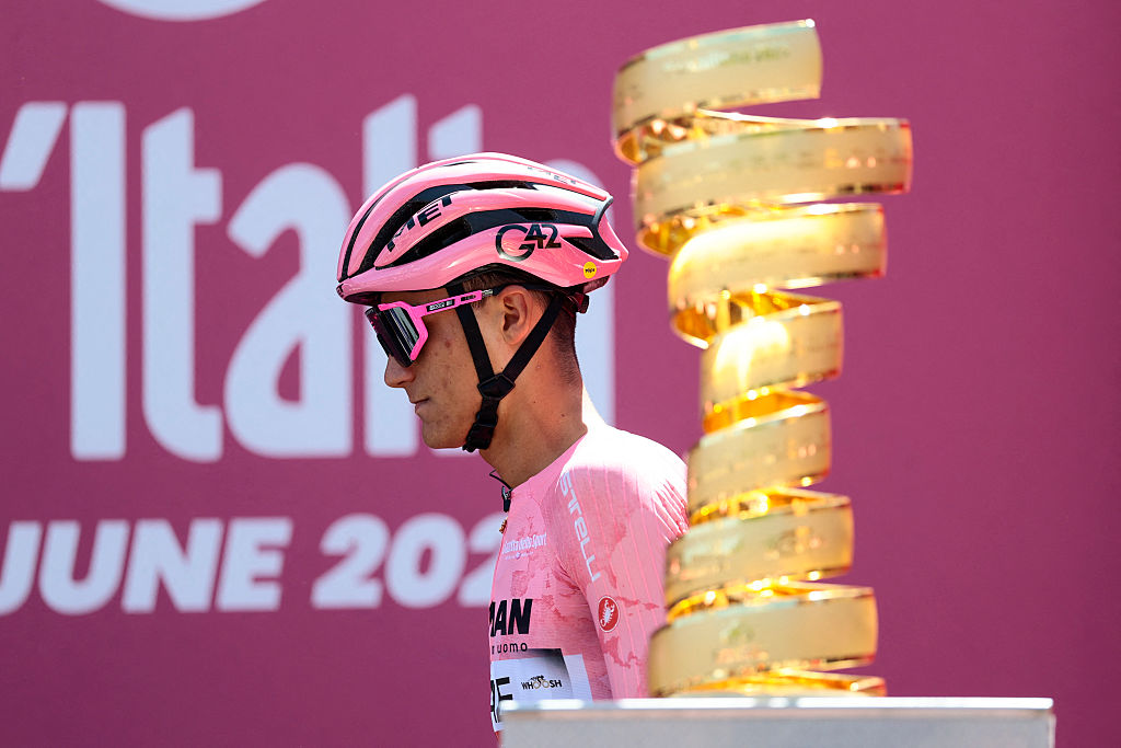 Isaac del Toro, in the pink jersey, pictured walking past the Giro d'Italia trophy