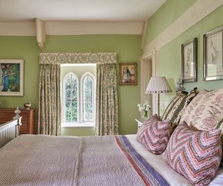 Spring bedroom with fresh green walls, printed curtains and pink floral bedding on bed