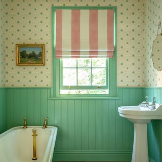 Bathroom with green panelling, wallpaper and pink and white striped blind