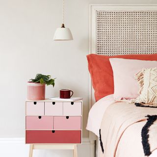 White bedroom with rattan headboard and pink side table