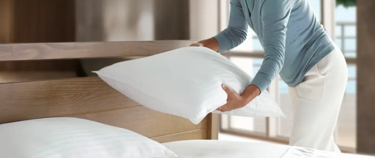 Woman placing white pillows on the bed