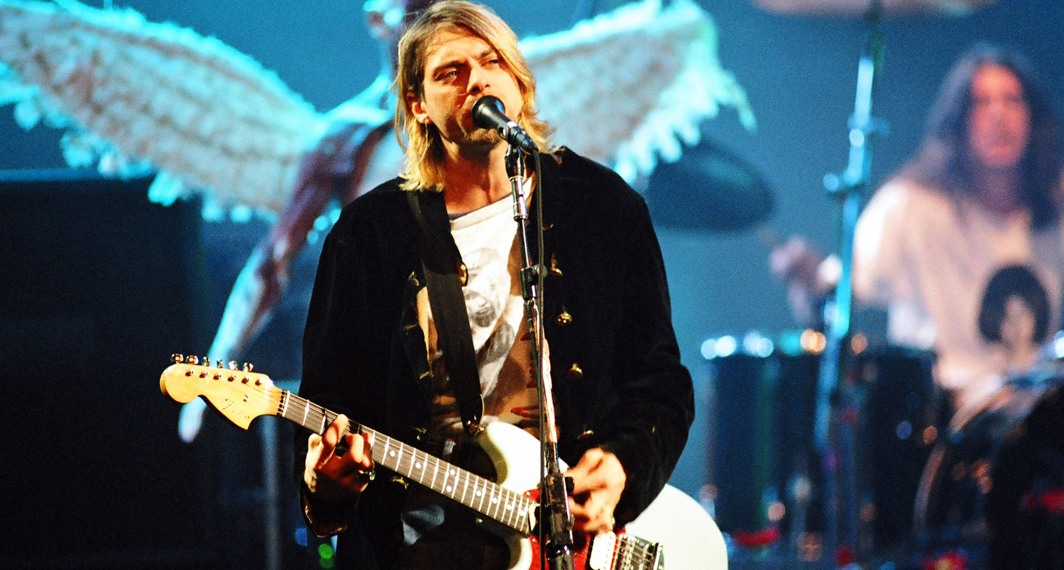 Kurt Cobain performs onstage with Nirvana in 1993 with angels wings in the background.