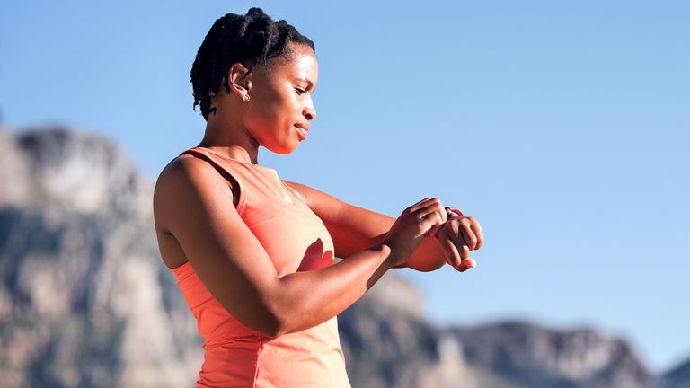 Fitbit types: woman outside checking fitness watch
