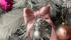 Close up of a pink ribbon bow on a silver artifical Christmas tree to show how to tie a perfect bow with ribbon