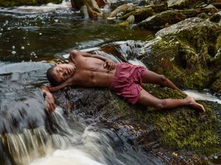 Child lying on rocks next to waterfall