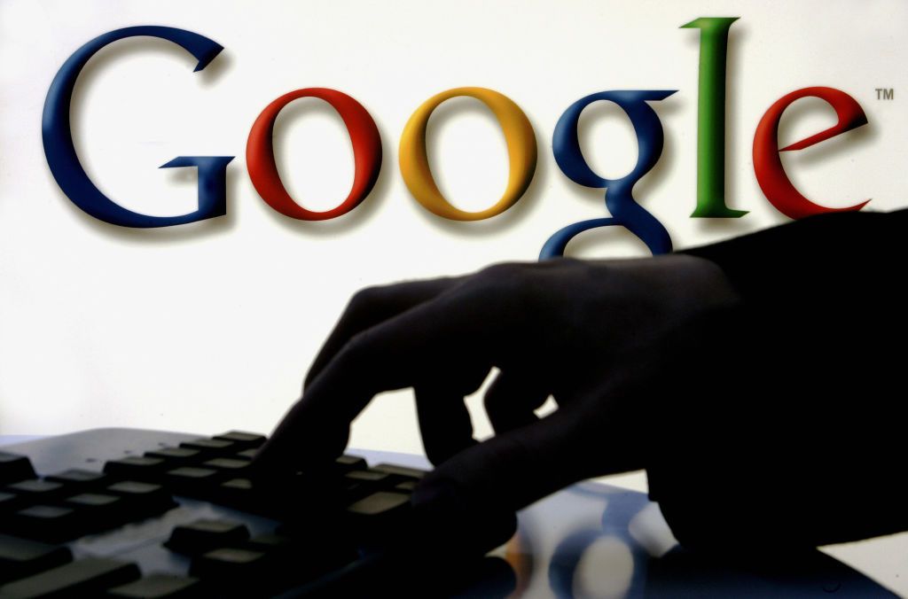 A woman types at a keyboard with Google&amp;#039;s logo seen behind