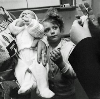 child standing looking at adults, baby in foreground, showing at the centre for british photography in london