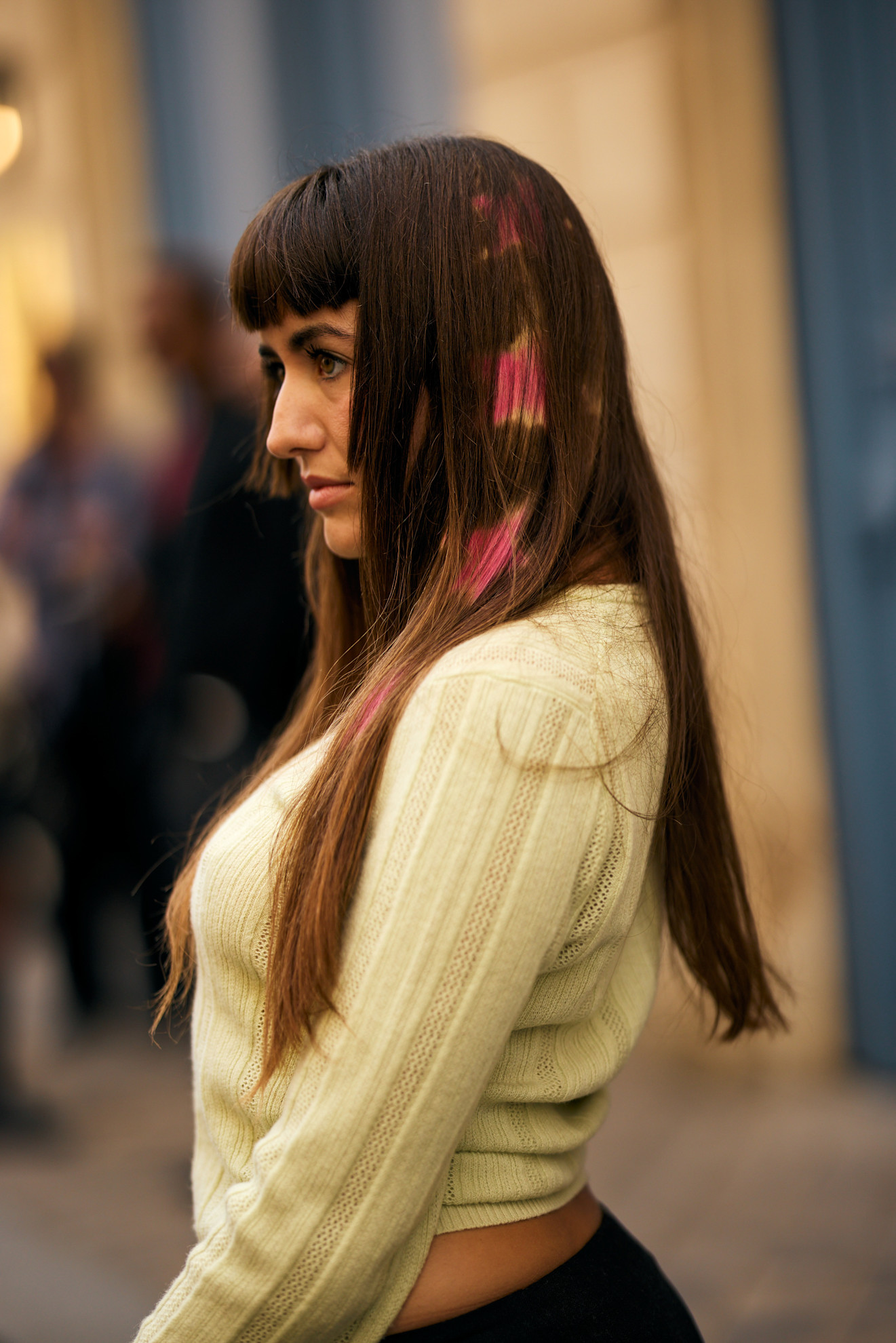 a white woman with brown hair with pink details in a yellow sweater