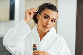 Portrait Of Young Woman Holding Face Serum Bottle