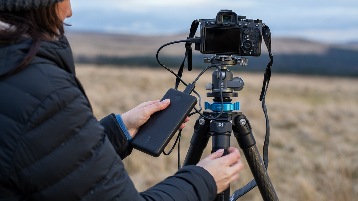 жена која користи Анкер ПоверЦоре Слим 10,000 повезану са камером у пољу