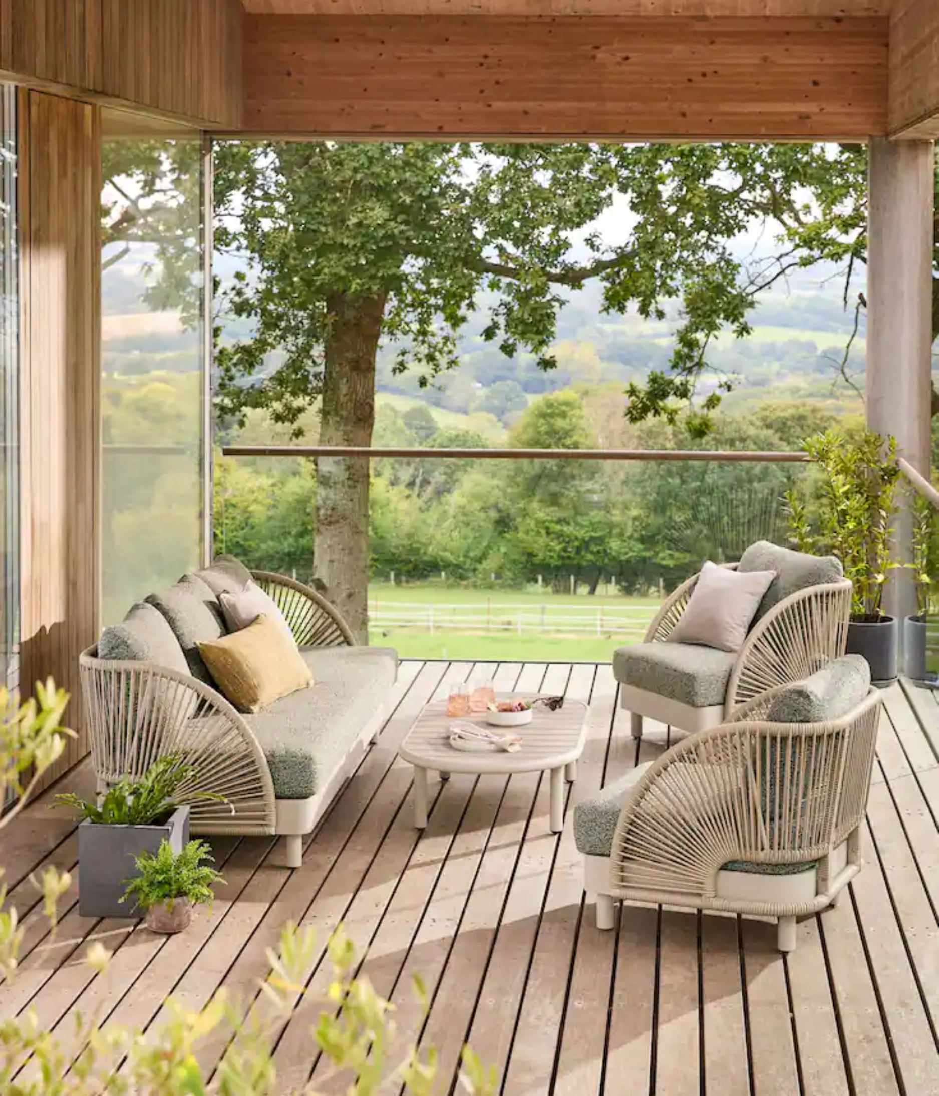 rattan and boucle outdoor furniture on a terrace overlooking the countryside