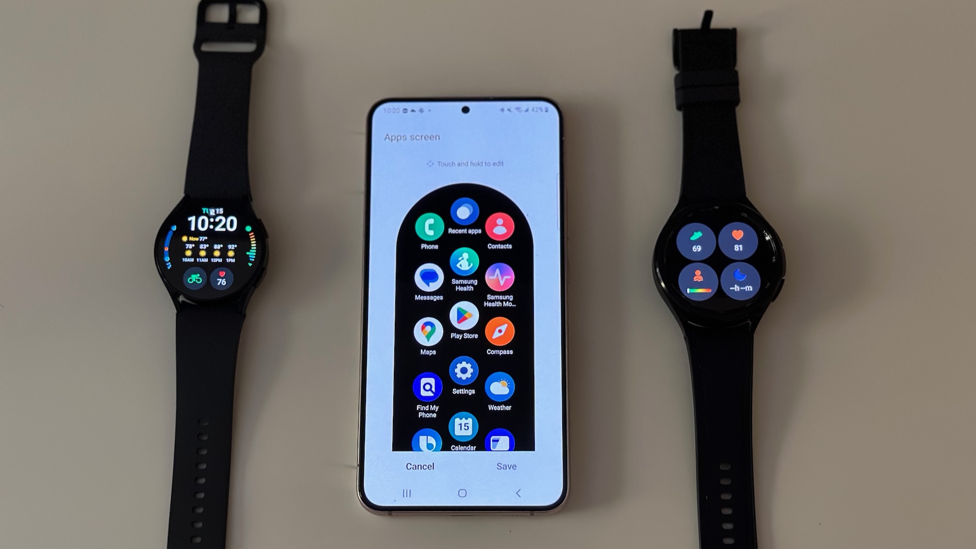 The Samsung Galaxy Watch 6 and Watch 6 Classic, sitting on either side of a Galaxy S22+ phone showing the Galaxy Wearable app, specifically the option to edit app order on a Galaxy Watch