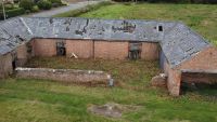 A dilapidated brick cottage surrounded by greenland on a building plot