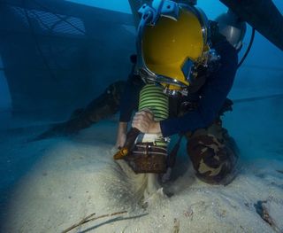 U.S. Navy Diver 1st Class Scott Johnson dredges an excavation site with a Venturi vacuum system off the coast of Koror, on Jan. 24.