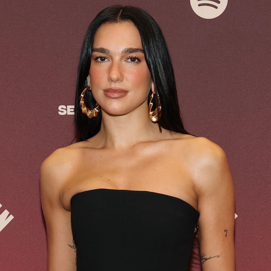 Dua Lipa wearing a black strapless dress with hoop earrings 