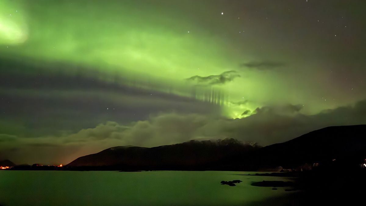 green curtain of light with small pillars along one edge as the aurora fills the sky.