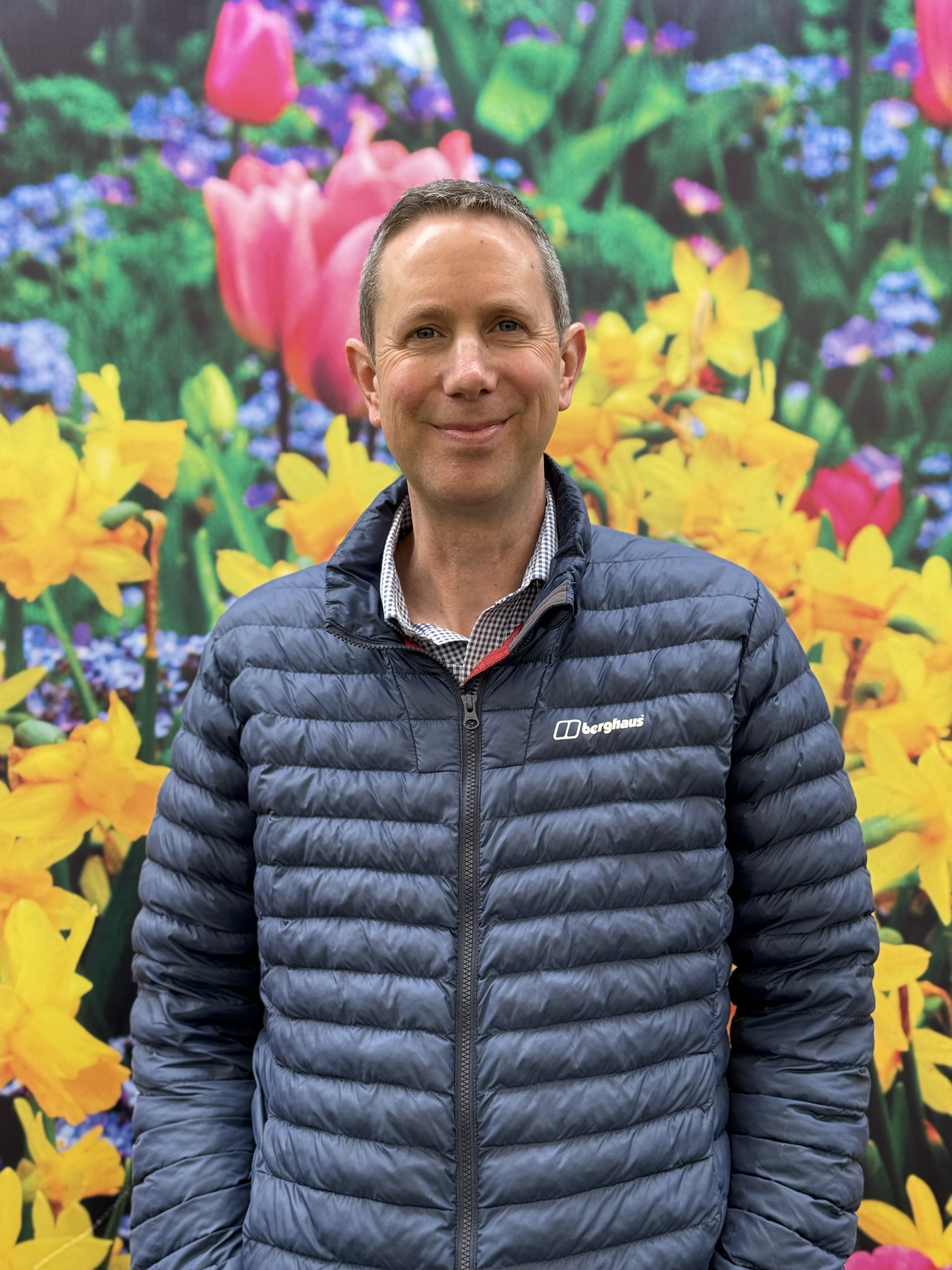 man smiles to camera in a coat