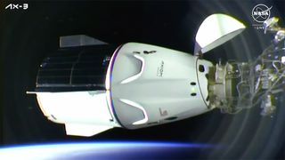 A white and black space capsule docks at the international space station