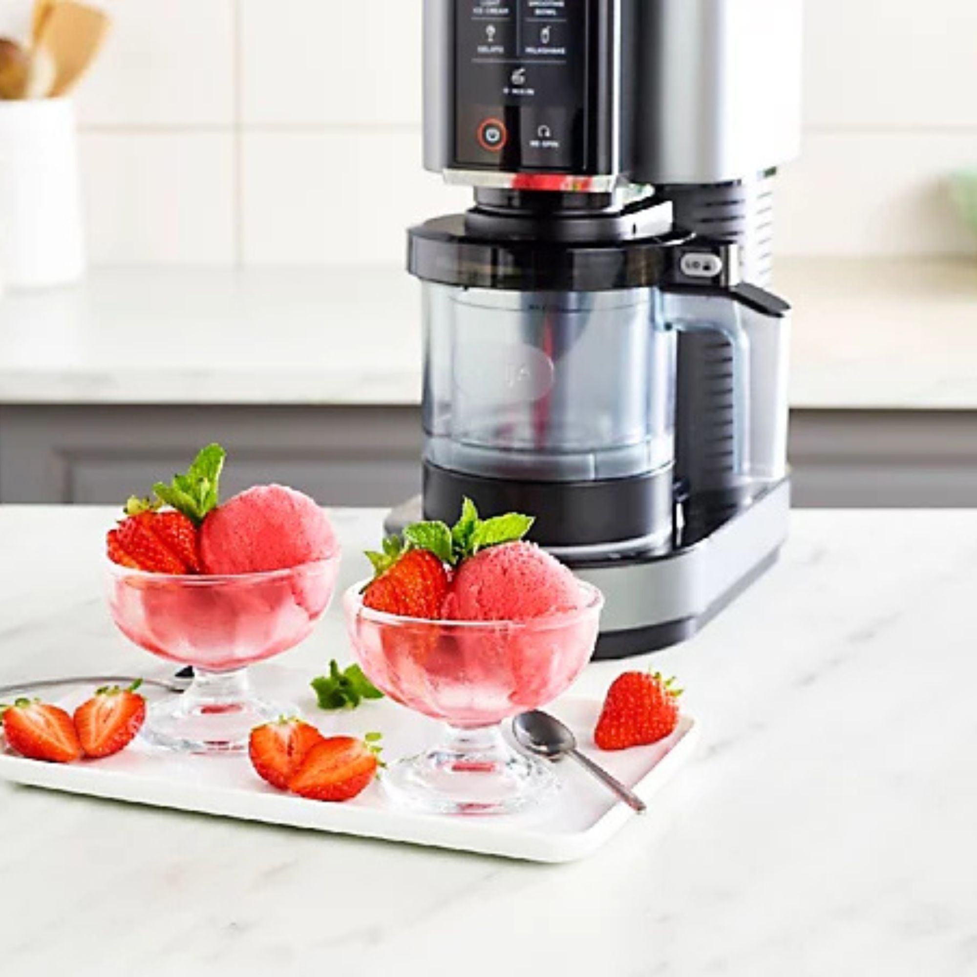 Two pots of strawberry sorbet in front of a Ninja Creami. 