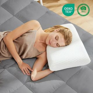 A woman lying on the EDX Memory Foam Pillow on a gray duvet. 