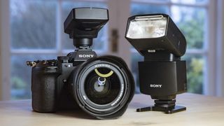 Sony A9 III with wireless radio commander alongside the Sony HVL 46RM flash on a wooden table
