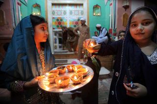 Hindu children held earthen lamps called diyas to celebrate Diwali.