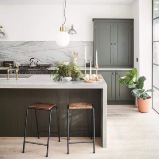 Large kitchen with sage cabinets and a large marble-topped kitchen island