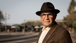 David Suchet in a brown hat and jacket at a railway station in Travels with Agatha Christie and Sir David Suchet.